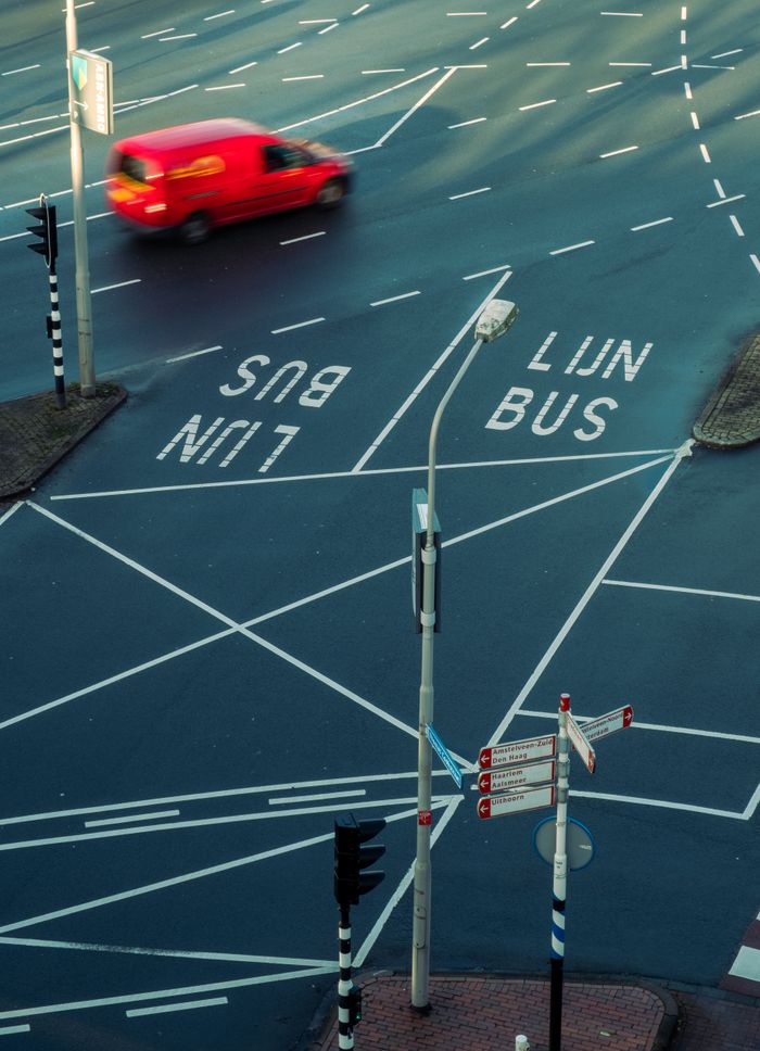 Home High-angle view of a busy city intersection with bus lanes and moving red car, showcasing urban traffic patterns.