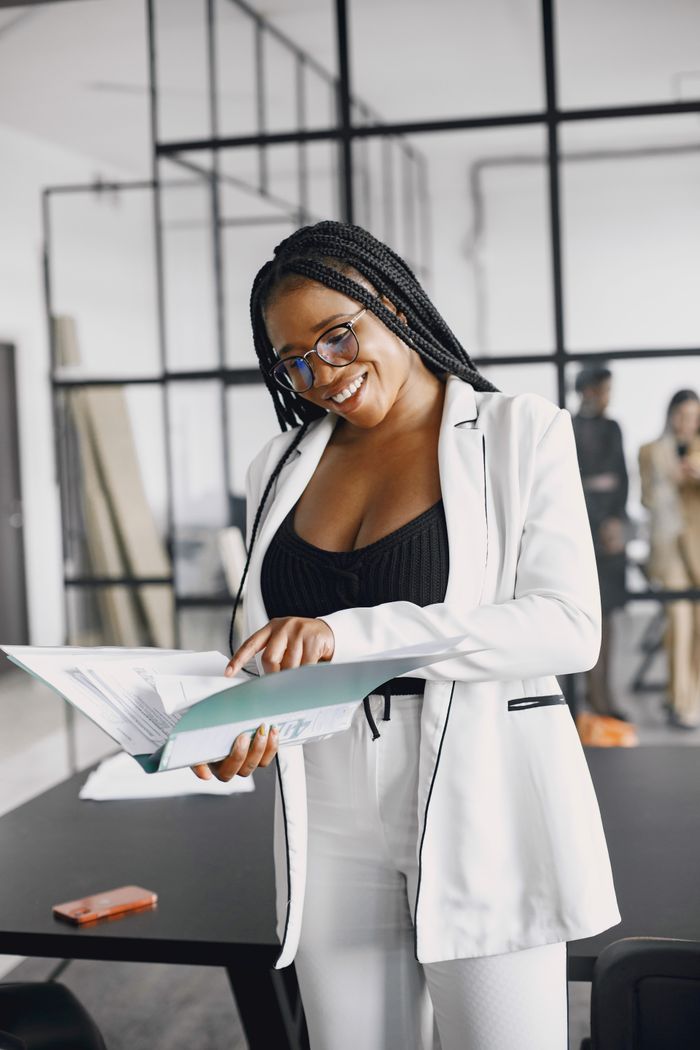 Professional woman in a white blazer reviewing documents in a modern office setting.